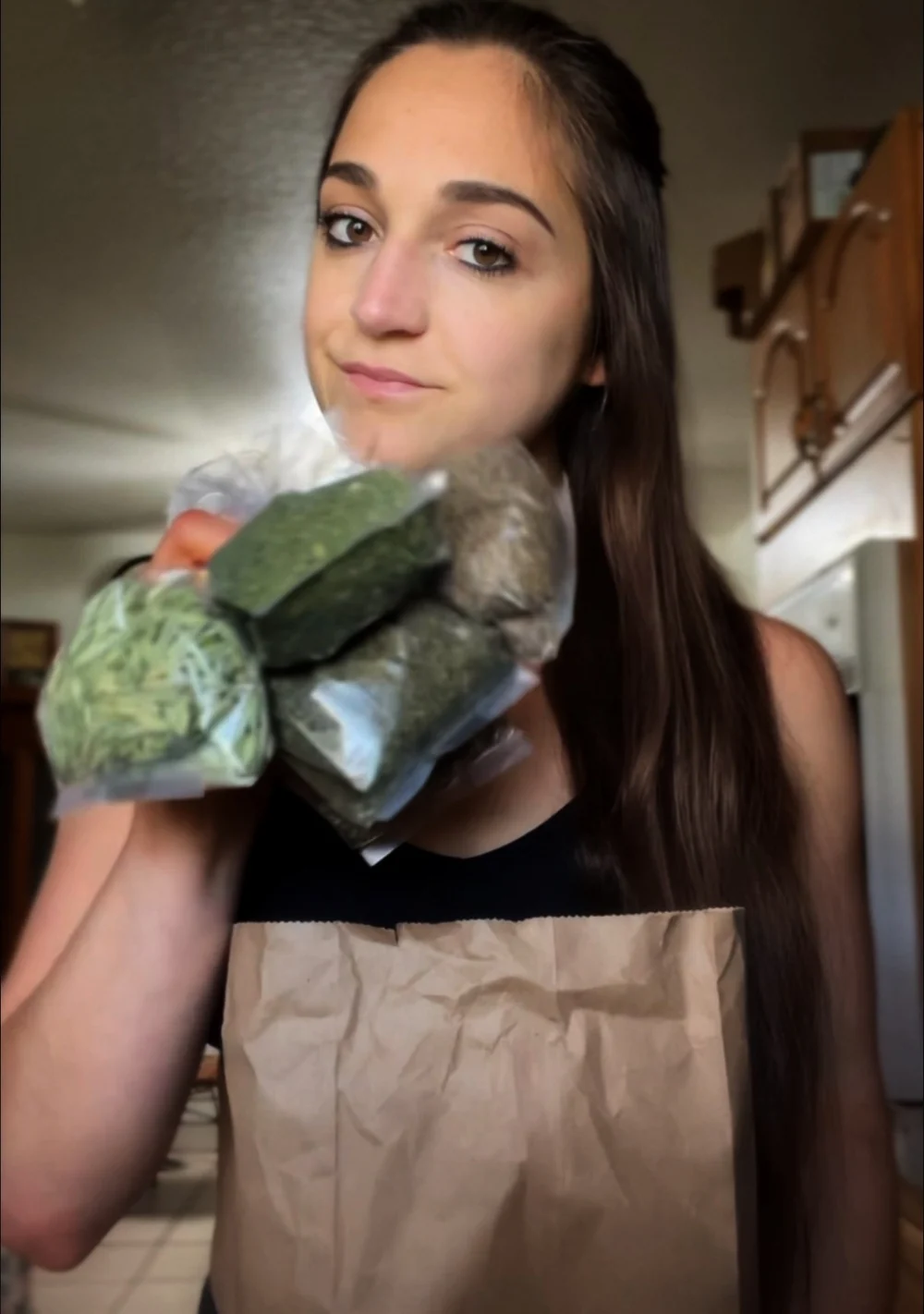 Hannah Howerton holding fresh herbs and vegetables in her kitchen